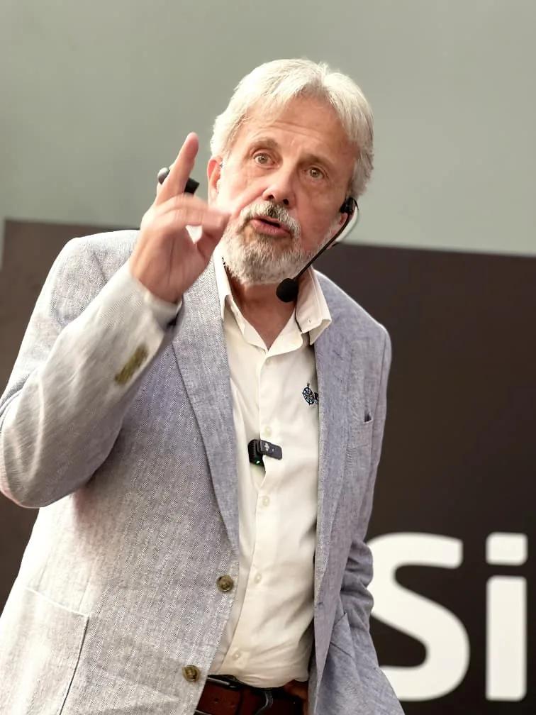 Eduardo Martí hablando con traje gris y micrófono de solapa