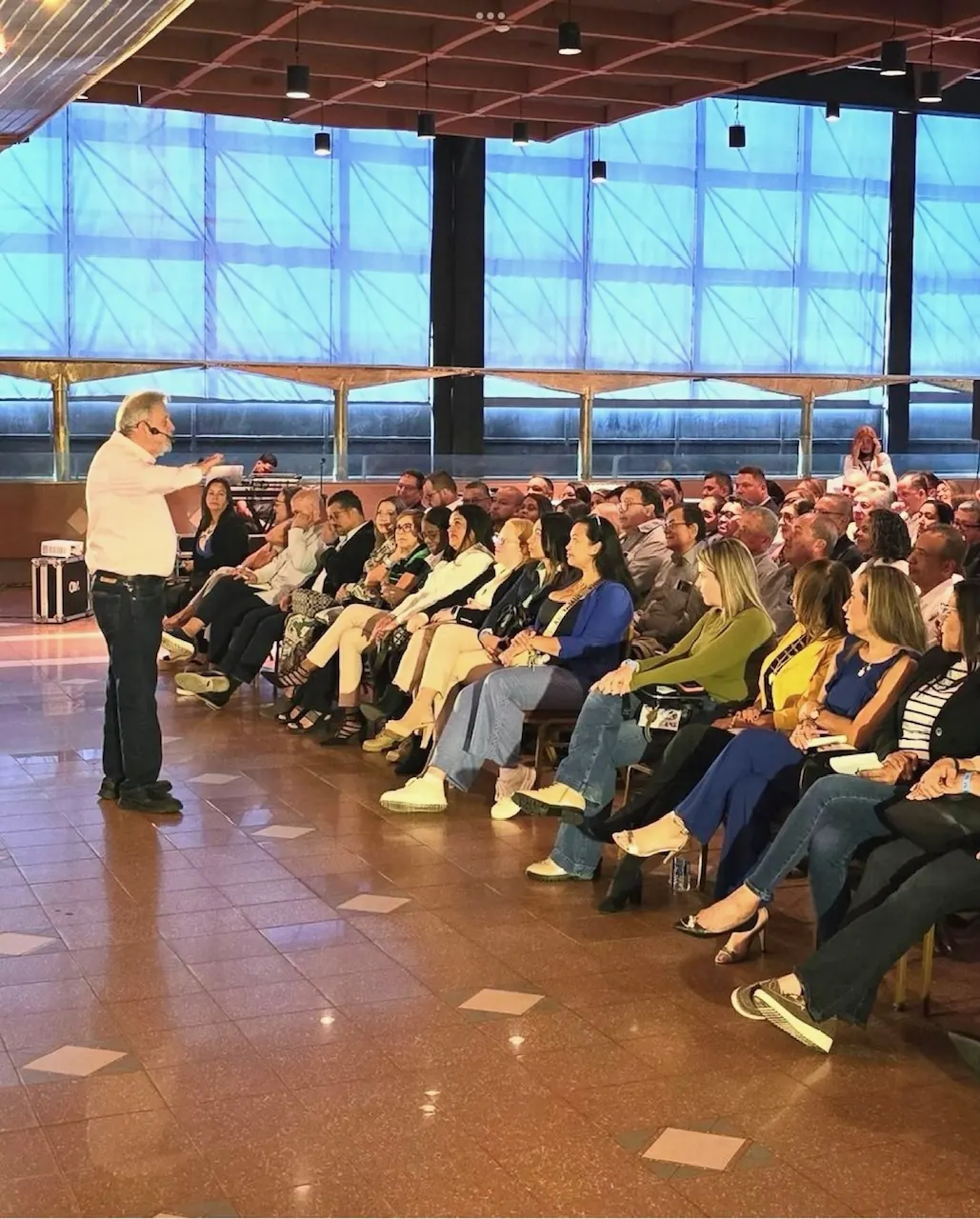 Público sentado en semicírculo en una sala luminosa